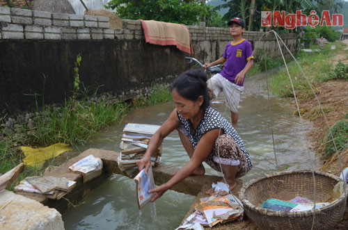 Người phụ nữ này đang lôi đống sách vở trong bùn lầy, mang ra khe rửa lại cho con học.
