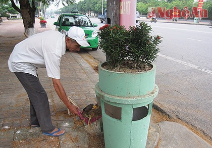 Người dân bỏ rác thải vào bồn rác trên vỉa hè đường Hồ Tùng Mậu