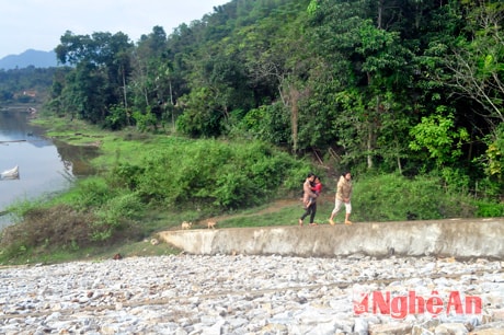 Không có đường đi, người dân vùng lòng hồ phải leo lên bờ kè công trình hồ chứa nước để ra ngoài.