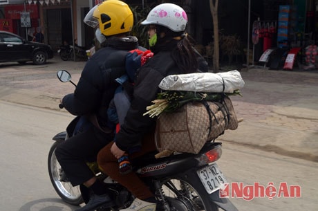 Gia đình nhỏ buộc lá dong, lạt giang sau xe để gói bánh chưng.