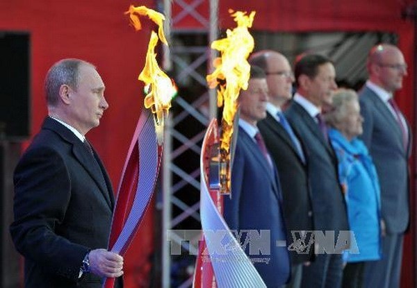 Tổng thống Nga Vladimir Putin giương cao ngọn đuốc Olympic Sochi 2014 trong buổi lễ rước đuốc tại Moskva. (Nguồn: AFP/TTXVN)