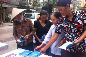 Nữ lao động di cư tại chợ Long Biên, Hà Nội đang xem tài liệu tư vấn về sức khỏe, pháp luật