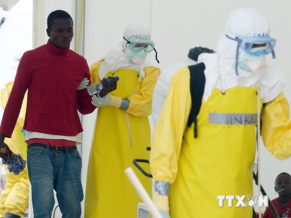 Nhân viên y tế trong trang phục bảo hộ giúp bệnh nhân nghi nhiễm Ebola tại bệnh viện Elwa ở Monrovia, Liberia ngày 7/9 vừa qua. (Ảnh: AFP/TTXVN)