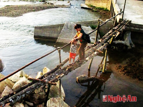 Bà mẹ bản Kim Hồng dìu con qua cầu đến lớp.