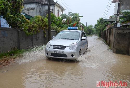 Vì quốc lộ 1A đang thi công, nhiều phương tiện đi đường tắt qua xóm 18B, xã Nghi Liên, thành phố Vinh trong cảnh ngập nước.