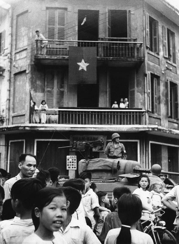 Lính Pháp trên xe tăng chuẩn bị rút khỏi Hà Nội cạnh một nhà dân treo cờ đỏ sao vàng.
