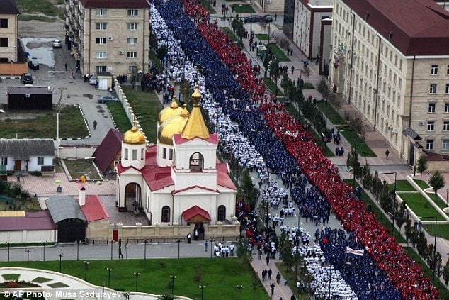 Đoàn người mang theo cờ Nga và cờ Chechnya trong lễ diễu hành. Ông Putin tới Siberia hôm 6/10 và dành một ngày nghỉ trong ngày sinh nhật 7/10 tại đây. Đây là lần đầu tiên ông nghỉ ngơi trong 15 lần sinh nhật gần đây. Năm ngoái, ông gặp các nhà lãnh đạo của APEC, uống rượu sake với Thủ tướng Nhật Shinzo Abe và dùng bánh sinh nhật cùng Chủ tịch Trung Quốc Tập Cận Bình. Ảnh: AP