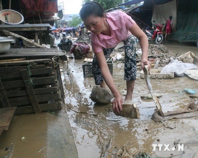 Dọn dẹp bùn rác sau khi nước lũ rút. Ảnh: TTXVN