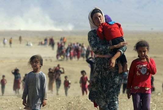 Một người phụ nữ thuộc dân tộc Yezidi đang bồng con chạy trốn từ khu vực Sinjar đến biên giới Siria hôm 11 tháng 8. Ảnh: Reuters/Stringer/Iraq.