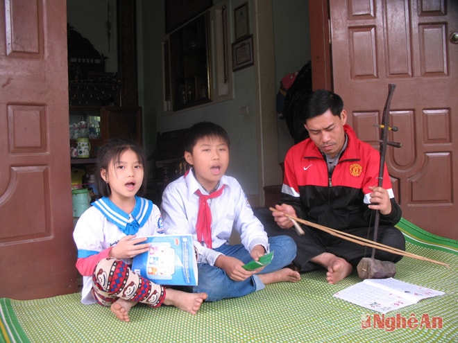 Em Đặng Tuấn Kiệt (giữa) tập hát dân ca với bố.