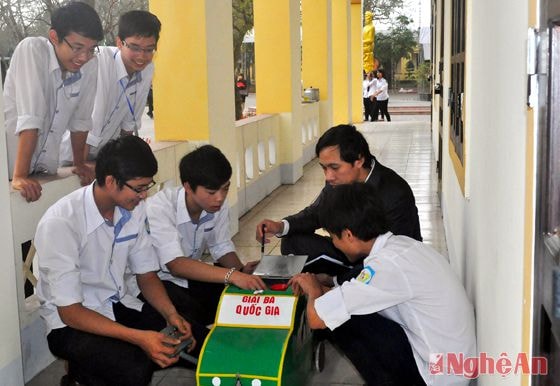 Thầy giáo Mai Văn Quyền và các học sinh bên công trình “Máy cào lúa và hút dẹp”.  