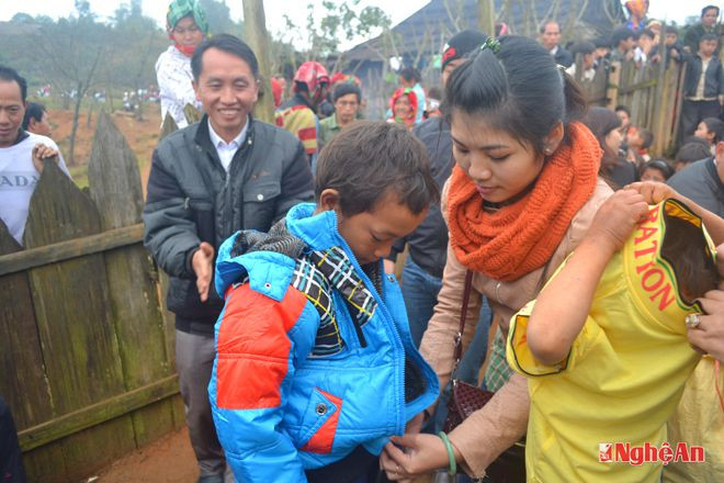 Một bạn thiện nguyện từ dưới xuôi lên đang khoác chiếc áo ấm mới cho học sinh. 