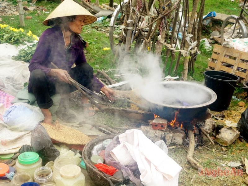 Ở một góc chợ, bà hàng nhuộm quần áo cũ thành quần áo mới đang nổi lửa nấu nồi thuốc nhuộm