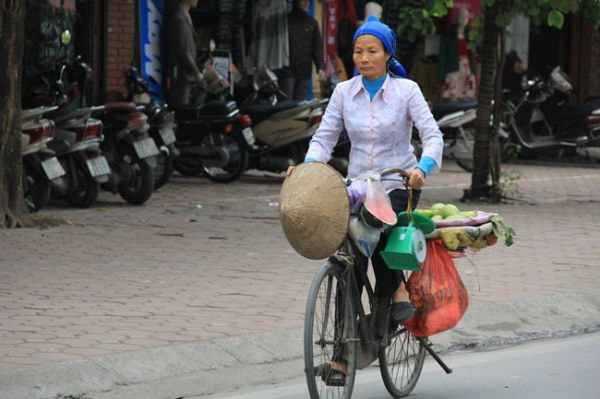 Người phụ nữ tảo tần đạp xe bán hoa quả, tấm áo mong manh và gương mặt thấm mệt.