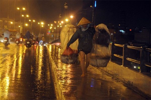 Gánh hàng rong của người phụ nữ về muộn trong đêm mưa Sài Gòn.