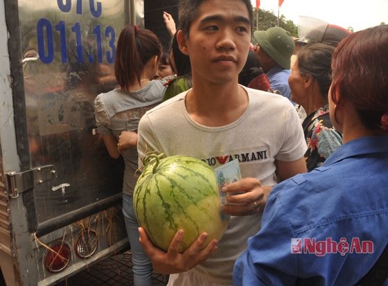 một thanh niên vui mừng vì sau một thời gian xếp hàng đã mua được một trái dưa ưng ý