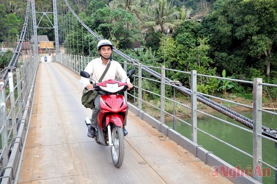 Ông La Hồng Muôn vượt cầu bản Lau (xã Thạch Giám- Tương Dương) để mang thông tin đến với bà con nhân dân