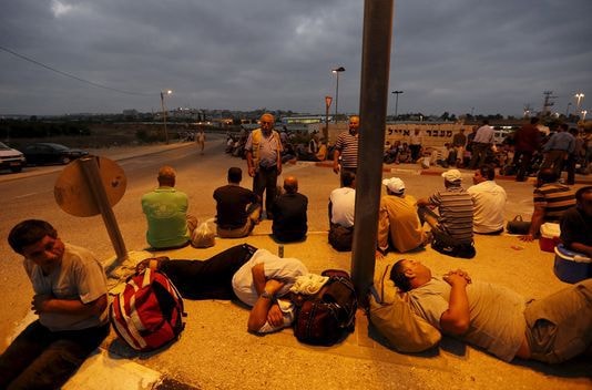 Những người lao động Palestine đang chờ xe buýt để quay trở về nhà ở Bờ Tây sau một ngày làm việc. Ảnh: Reuters