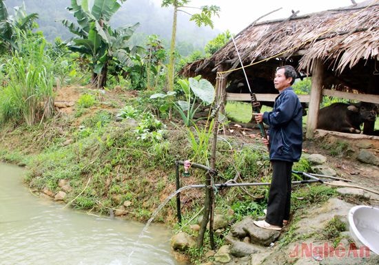 Ông Vi Văn Hùng đang sửa đường nước dẫn vào ao.