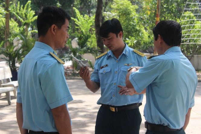 Một nhóm các phi công đang nghiên cứu về bài bay của mình trên khu vực sân rộng có vẽ các đường bay và ôn bài với mô hình máy bay Su-30MK2 trên tay. (Ảnh Tuổi Trẻ)