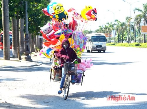 Vừa đạp ngược gió, giữa trời nắng chang chang, hai chị em (trong ảnh) vừa bịt kín nhằm ‘trốn’ cái nắng bỏng rát để bán hàng, dọc đường Đại lộ Lê Nin để kiếm thêm thu nhập vào những ngày nghỉ hè 