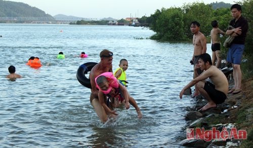 Bãi sông rộng rãi là cơ hội cho nhiều phụ huynh dạy trẻ học bơi. Trong ảnh, ông nội đang cố gắng giúp cháu nhỏ làm quen với làn nước.