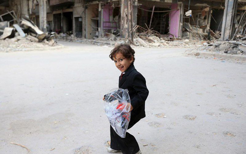 Một cậu bé ở vùng Jobar, ngoại ô Thủ đô Damacus, Syria hớn hở mang bộ quần áo mới trong ngày cầu nguyện Eid Al Fitr. Ảnh: Reuters