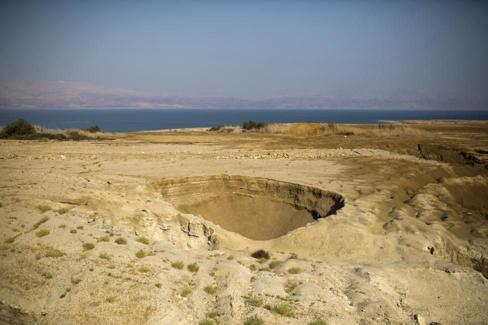 Ảnh chụp hố sụt bên bờ Biển Chết, Israel hôm 27/7. Biển Chết đang thu hẹp lại, và khi nước biển bốc hơi với tốc độ hơn 1m/năm, hàng trăm hố sụt có kích thước lên đến kích thước của sân bóng rổ và có thể có chiều sâu tương đương 2 tòa lầu, xuất hiện trên bờ biển.