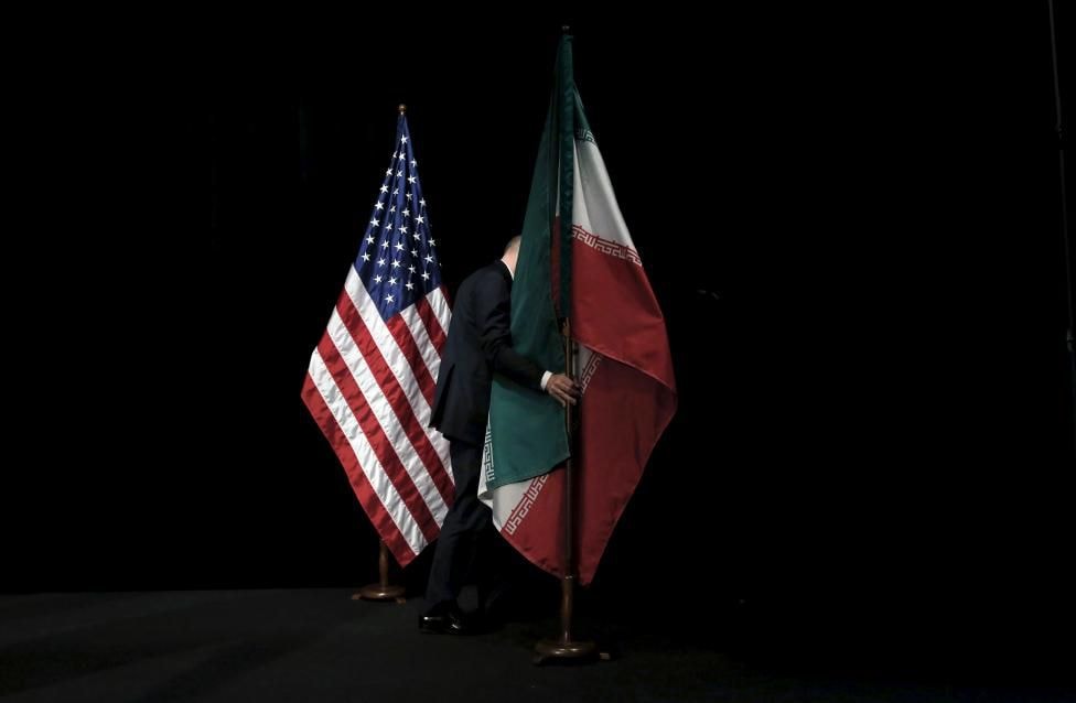 Một nhân viên thu dọn quốc kỳ Iran trên sân khấu sau khi các bộ trưởng và đại diện các nước Mỹ, Iran, Trung Quốc, Nga, Đức, Pháp và EU chụp ảnh lưu niệm sau các cuộc đàm phán hạt nhân Iran và đạt được thỏa thuận “lịch sử” tại Vienna, Áo hôm 14/7.