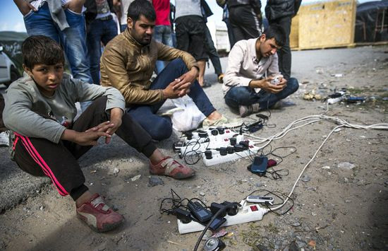Người di cư tại trại tị nạn ở Calais đang chờ sạc điện thoại.