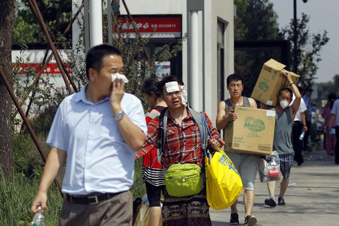Sáng nay, các cư dân sống gần hiện trường vụ nổ mang theo đồ đạc, hành lý di dời tới nơi an toàn. Ảnh: China Daily.