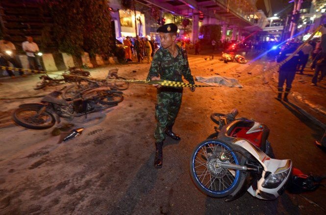 Một cảnh sát Thái Lan đang đứng tại hiện trường xảy ra vụ đánh bom ở Bangkok - Ảnh AFP