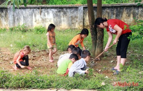 Học sinh và cô giáo Trường Tiểu học Nậm Càn (Kỳ Sơn), điểm trường bản Sơn Thành vệ sinh khuôn viên.