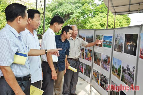 Các đại biểu xem triển lãm ảnh về đền Cờn và tiềm năng phát triển du lịch của Thị xã Hoàng Mai.