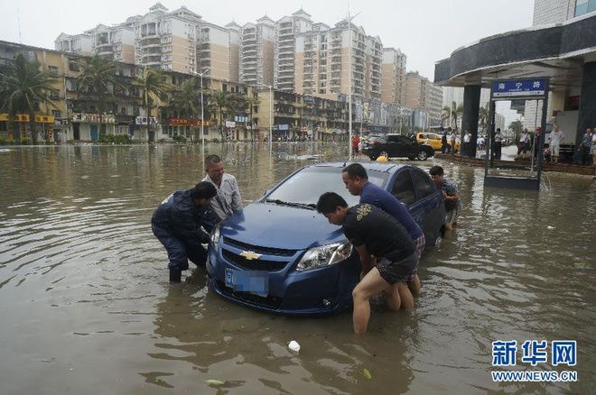 Người dân cùng nhau đẩy một chiếc xe bị ngập nước ở thành phố Trạm Giang. Ảnh: Xinhua