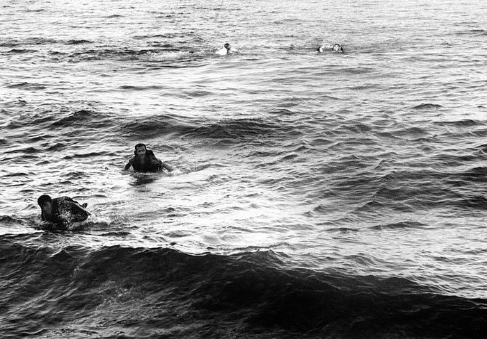 Những người sống sót vật lộn giữa con sóng sau khi chiếc thuyền chở họ bị lật úp. Nhìn ra xa hơn, một nhân viên cứu hộ Tây Ban Nha, nằm trong số những tình nguyện viên có mặt tại bãi biển này, bơi ra xa để cứu giúp những người khác.