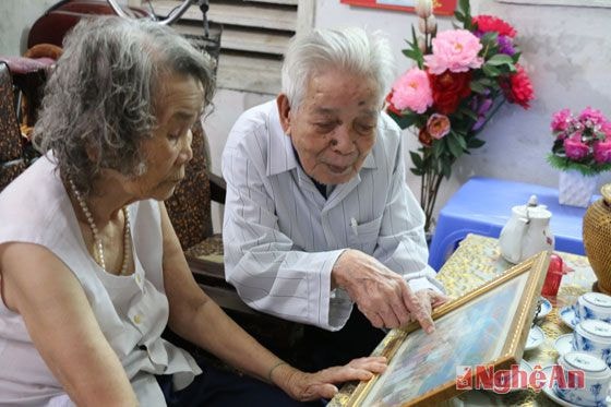 Thầy giáo Phạm Nhượng, nguyên hiệu trưởng trường THPT Huỳnh Thúc Kháng bên những bức ảnh lưu niệm về những ngày đứng trên bục giảng