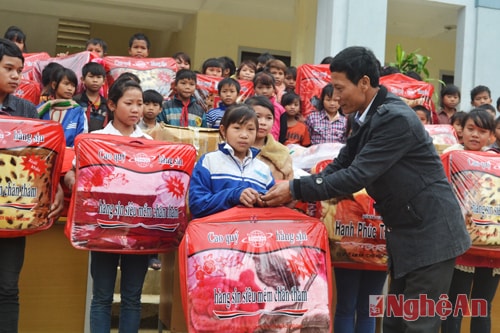 Đại diện đoàn công tác trao chăn ấm cho các em học sinh. 