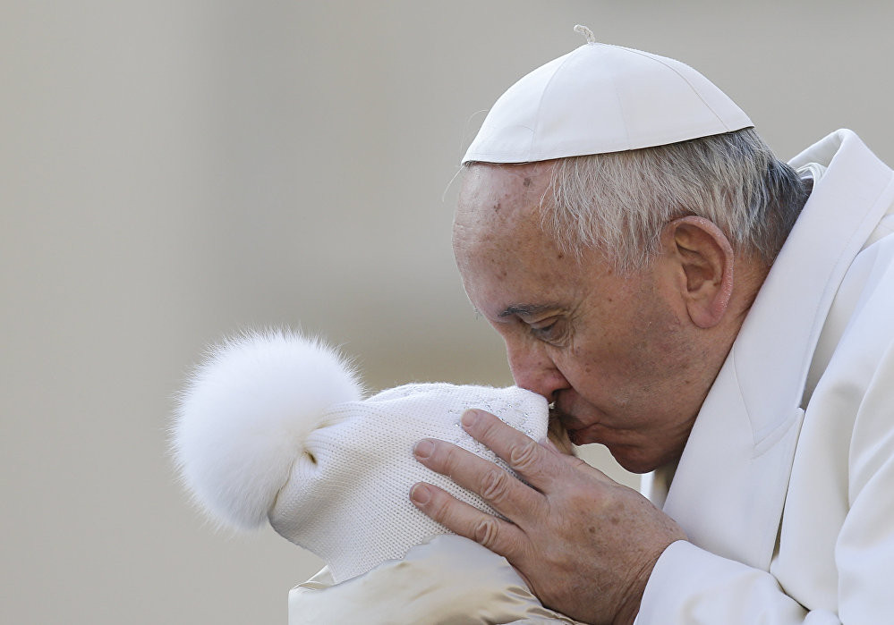 Giáo hoàng Francis hôn một đứa trẻ khi tới dự buổi tiếp kiến chung hàng tuần tại tòa thánh Vatican hôm 16/12.