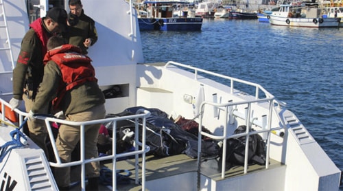 [Caption]Turkish coast guard officers arrive Jan. 21 at a port near Izmir with the bodies of migrants who drowned trying to reach Greece.(Associated Press)