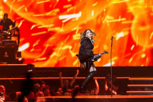 Madonna lí lắc ôm guitar bass phiêu trên sân khấu trong tiết mục Burning Up. Sự trẻ trung và phong cách mạnh mẽ của nữ ca sĩ 58 tuổi truyền cảm hứng cho khán giả ở nhiều thế hệ.