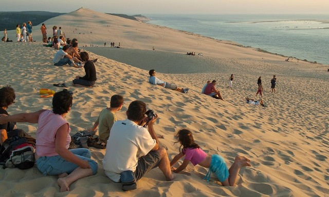 Ảnh 02. Dune du Pyla, Pháp Bãi biển Dune du Pyla - cồn cát lớn nhất của Châu Âu - hơn 100m đứng ở vị trí thứ 2. Chỉ với 1 giờ lái xe từ Bordeaux, bạn đã có thể trải dài tầm mắt trên bờ cát hoang sơ phản chiếu ánh mặt trời lấp lánh. Hãy bắt chuyến phà trên đê Arcachon đi dọc bờ biển đến Cap Ferret để có thể ngắm nhìn kĩ hơn bãi biển xinh đẹp này. Ngư dân ở đây còn phục vụ món hàu ngay tại bờ biển cùng với tôm, paté, bánh mỳ và rượu vang.