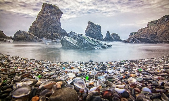 Ảnh 05. Glass Beach, California Bãi biển Glass Beach, California xếp vị trí thứ 5 mang phong cách hoàn toàn đặc biệt. Từ năm 1906 đến 1967, thủy tinh, các vật dụng và cả phuơng tiện đã bị đổ thẳng xuống biển. Một chương trình dọn dẹp sau đó đã loại bỏ kim loại và các chất thải không phân hủy, để lại những mảnh vỡ từ thủy tinh và đồ gốm được sóng đánh dạt lên bờ như những hòn đá nhiều màu. Ngày nay, bãi biển là một phần của công viên Quốc gia MacKerricher, và du khách không được phép lấy đi những 