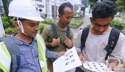 Construction workers looking at the mug shots of 27 Bangladeshi foreign workers who were arrested here under the Internal Security Act. (Photo: Ernest Chua/TODAY)