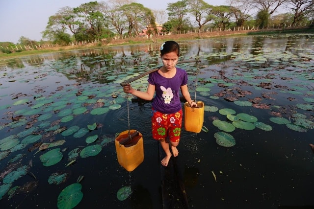 Bé gái gánh nước từ sông Dala, ngoại ô Yangon, Myanmar về cho gia đình.