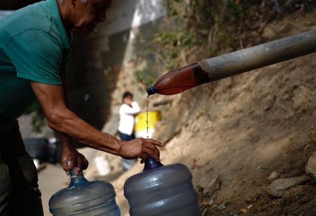 Người đàn ông hứng chút nước ít ỏi chảy ra từ con suối gần cao tốc dọc núi Avila ở Caracas, Venezuela.