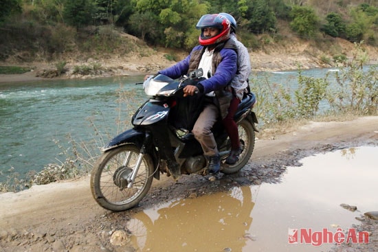 Giữa đường đầy các vũng bùn, người đi xe máy phải lách qua sát sông Nậm Mộ để đi.
