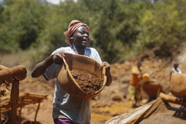 Phụ nữ cũng phải lao động nặng nhọc tại khu mỏ. Trong ảnh: Một phụ nữ bê chiếc chậu chứa đầy quặng để đưa đến khu lọc rửa.
