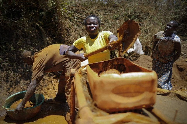Một phụ nữ khác xúc từng xẻng quặng vào các thùng rửa tự chế để tách kim loại quý tại mỏ Macalder, Tây Kenya.
