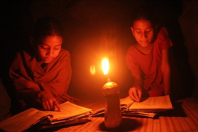 Hai em gái đang học bài vào buổi tối, dưới ánh đèn dầu ở ngôi làng nhỏ Netrok, Bangladesh.